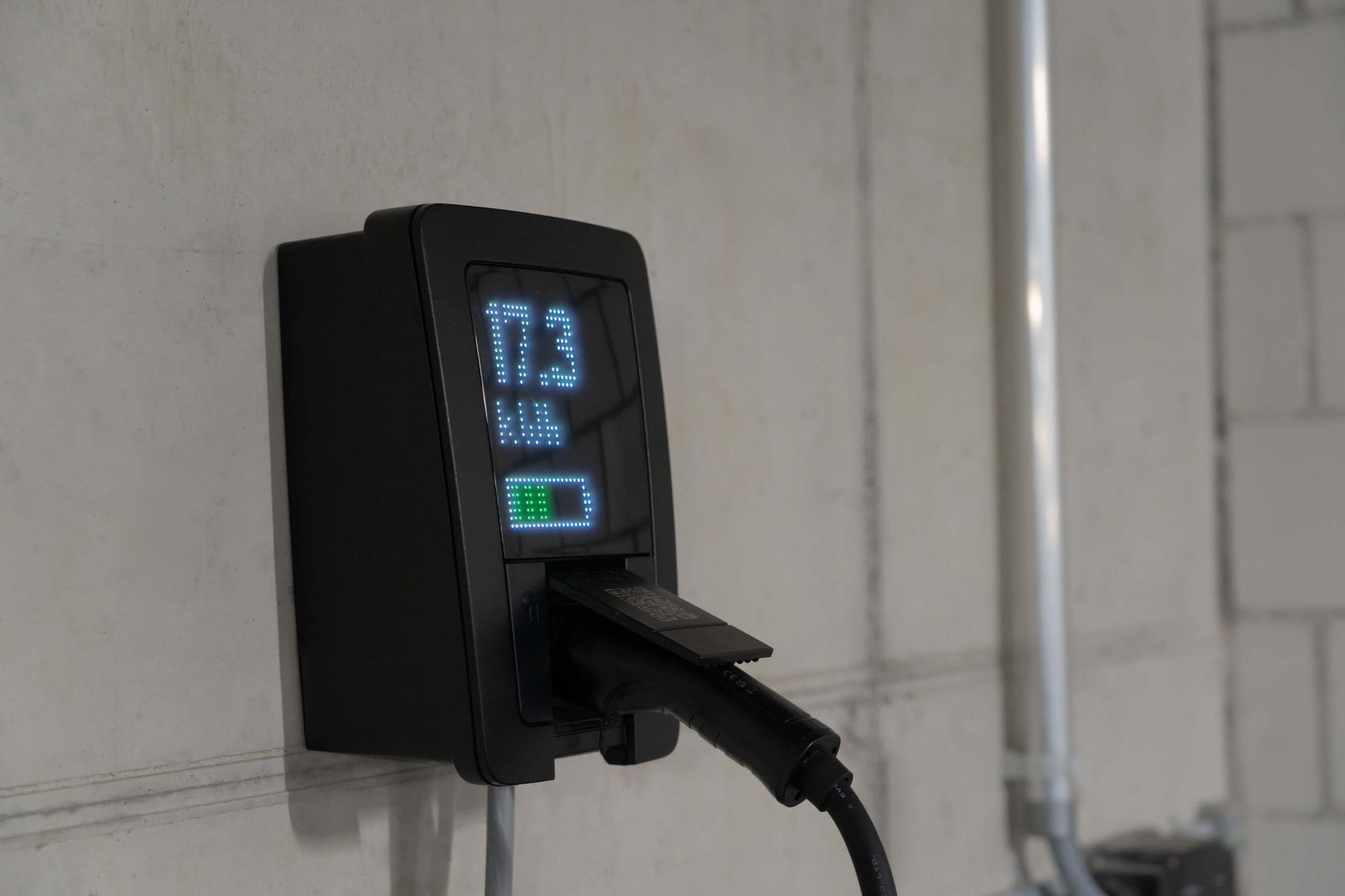 A wall-mounted car charger showing 17.3 kWh, its cable plugged in
