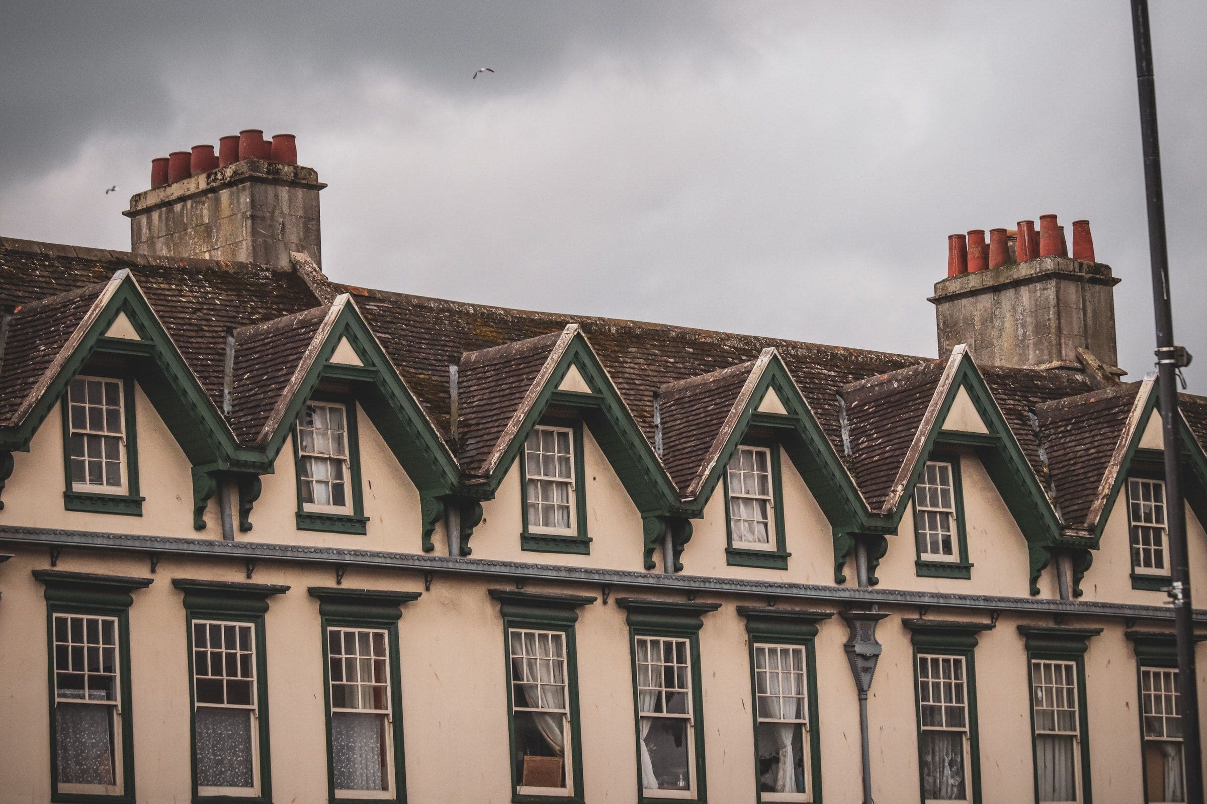 A row of gabled Victorian houses with tall chimneys under a grey sky
