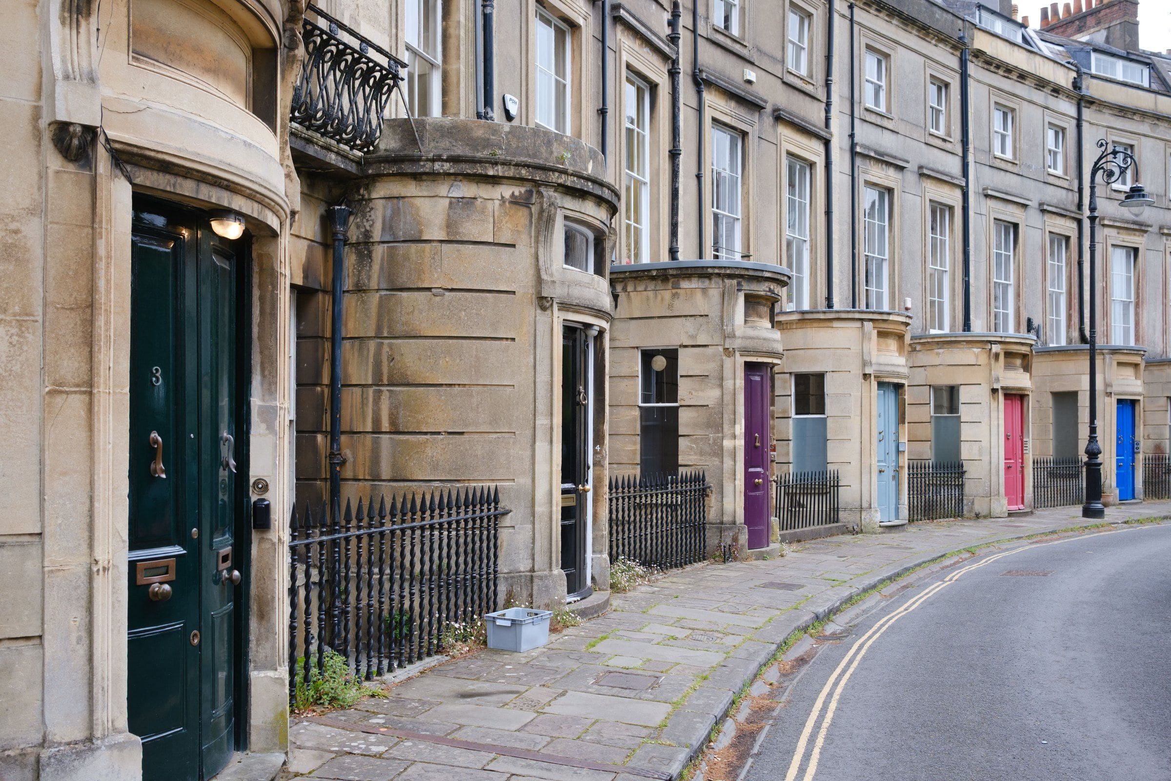 A curved Georgian terrace in pale stone with painted front doors