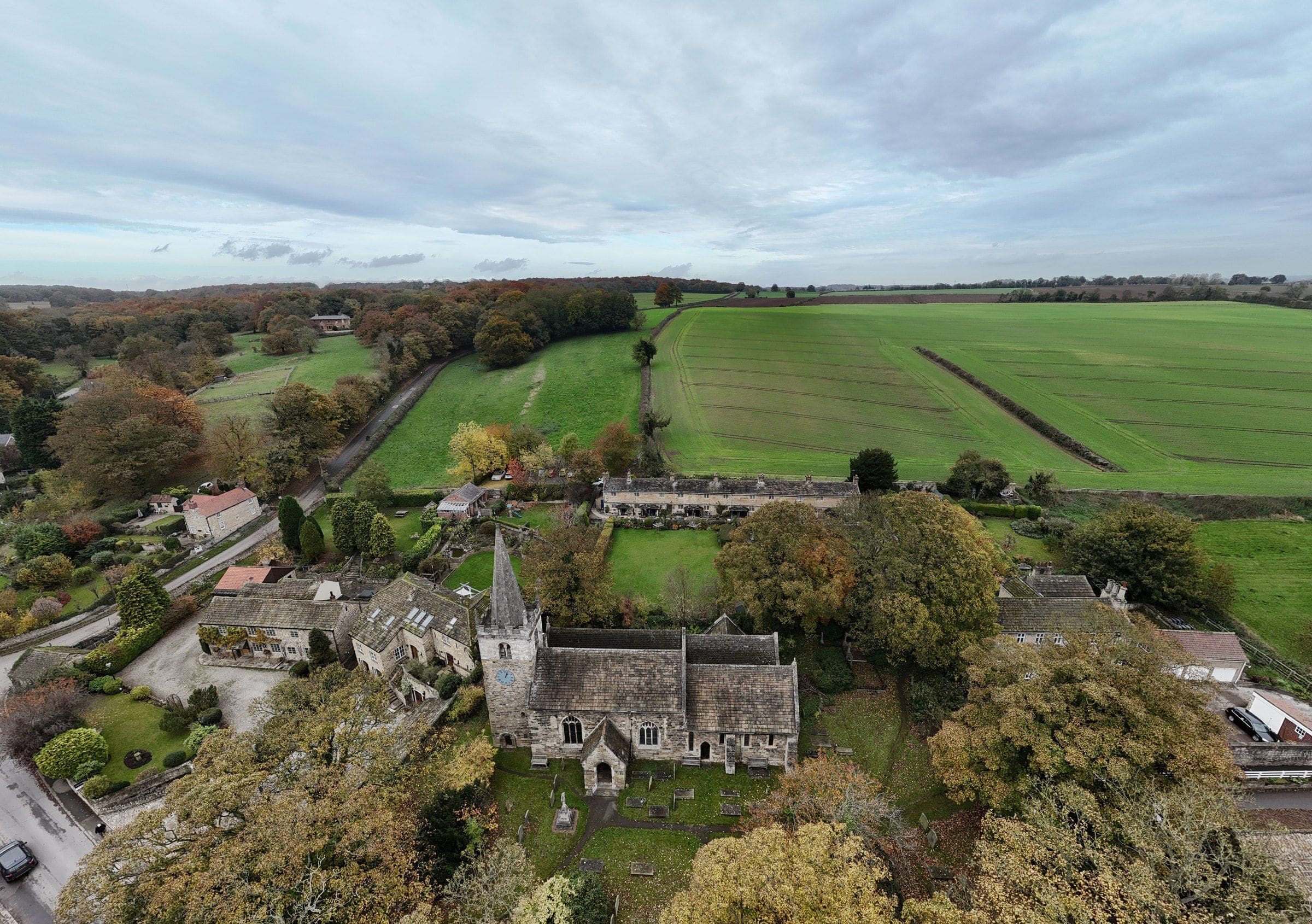 An English village and its church among fields, from the air