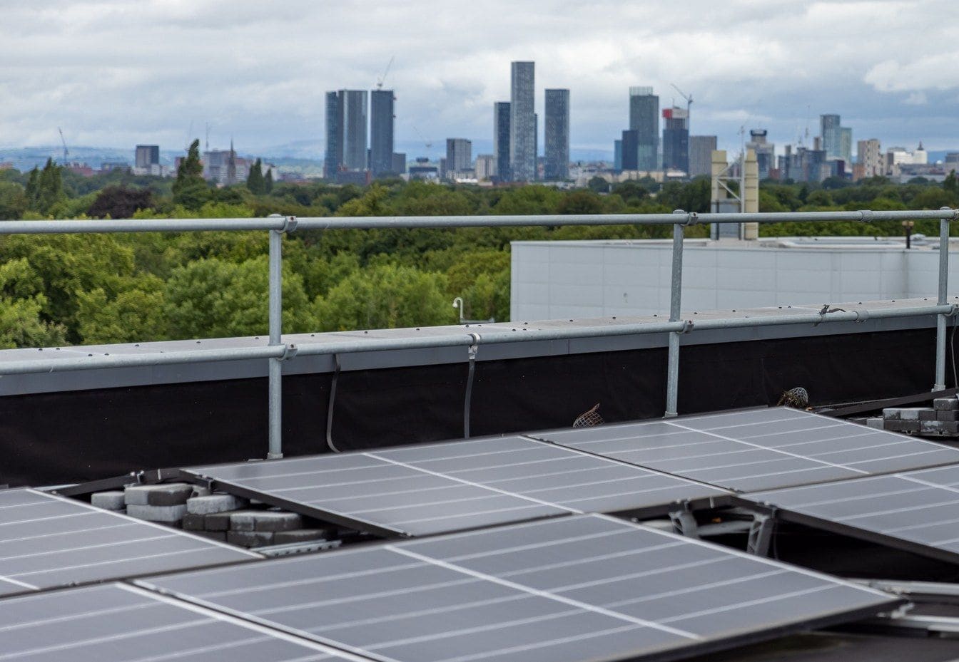 Solar panels on low frames across a flat roof, a city skyline beyond
