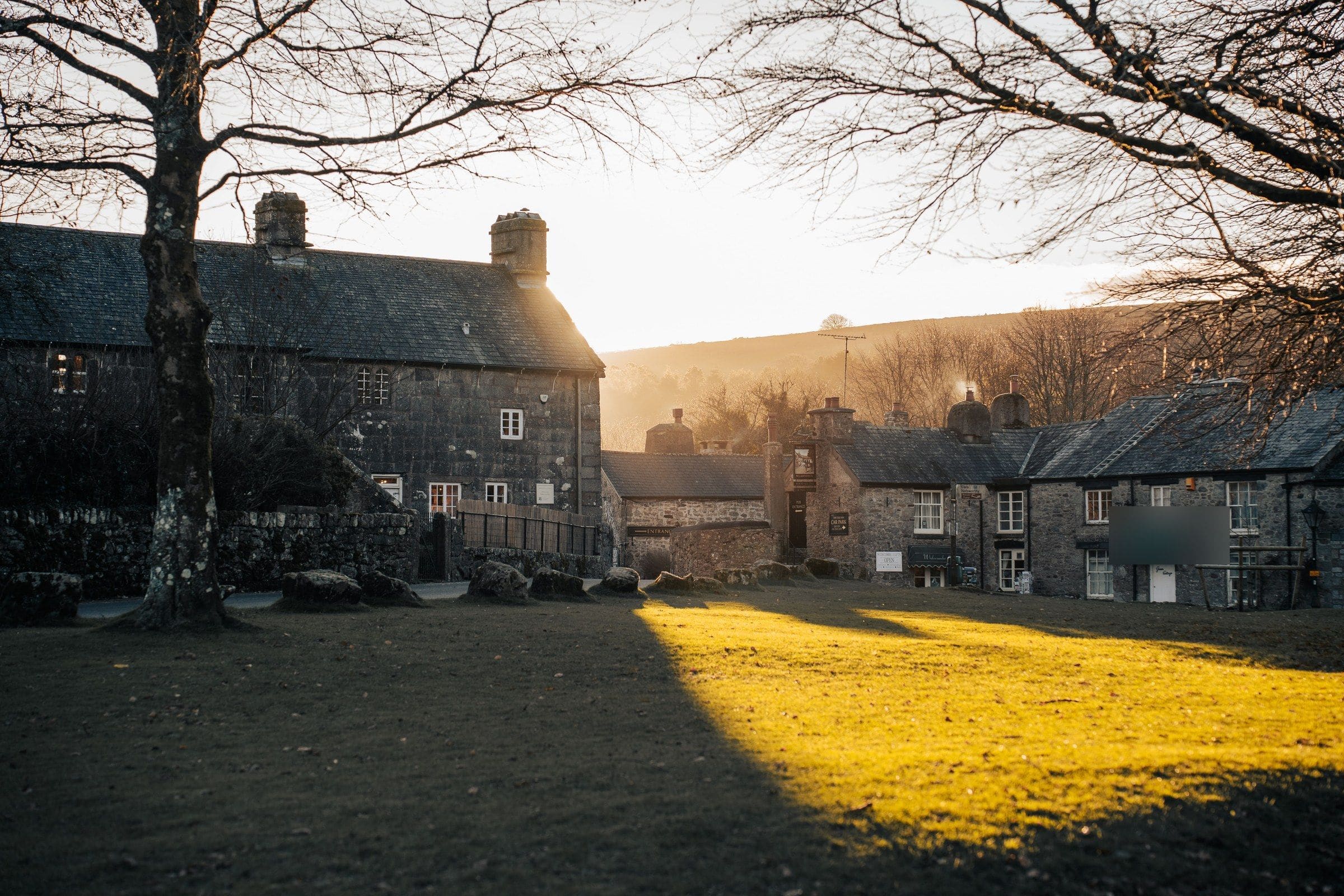 Low morning sun over stone cottages and a village green